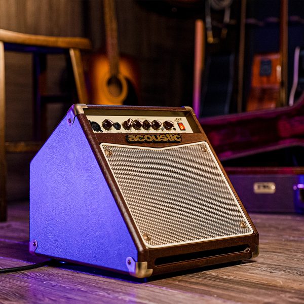 guitar case and guitar behind the A15V 15W acoustic amp and a stool in the side